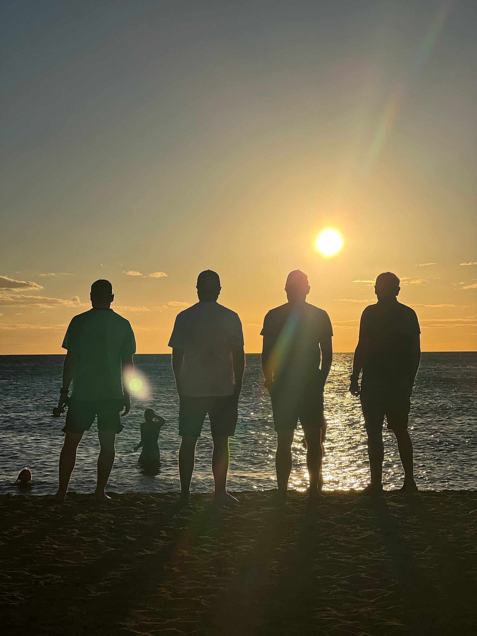 Team silhouettes on beach at sunset - representing our founding moment in Kona